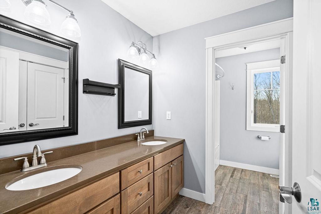 3879 Okerstrom Road Hermantown, MN 55811 - Photo 24 of 32 Bathroom with double vanity, dark wood finished floors, and bathing tub / shower combination