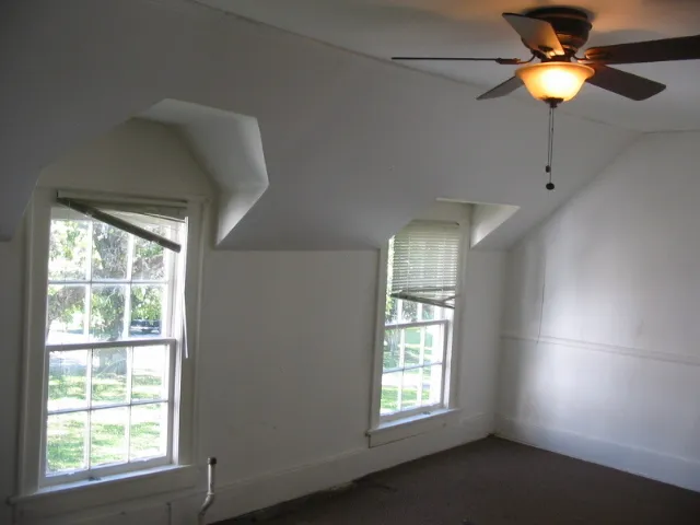 an empty room with windows and fan