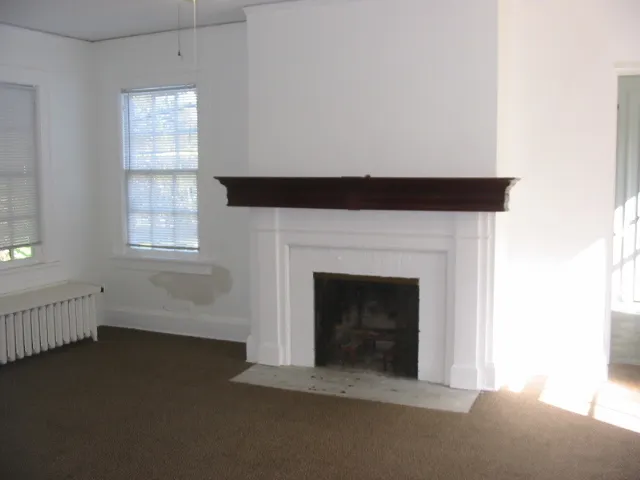 an empty room with windows and fireplace