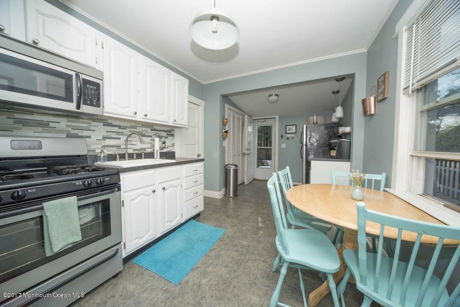 402 Maple Drive Belford, NJ 07718 - Photo 10 of 18 a kitchen with stainless steel appliances granite countertop a stove a sink dishwasher a dining table and chairs with wooden floor