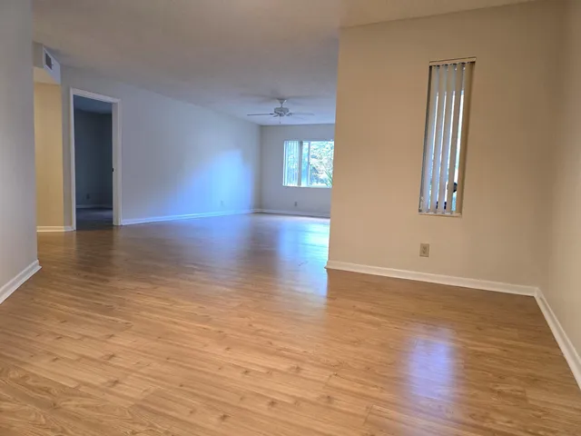 an empty room with wooden floor and windows