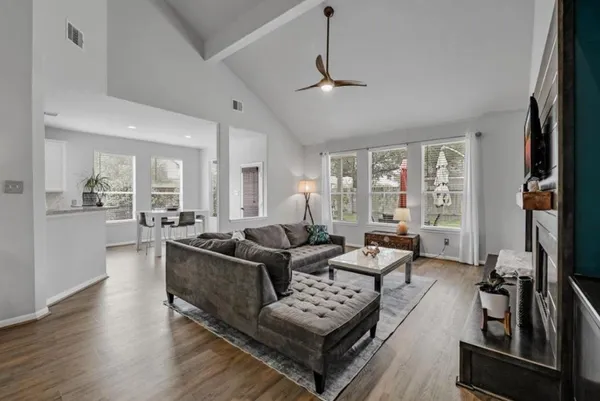 a living room with furniture a large window and wooden floor