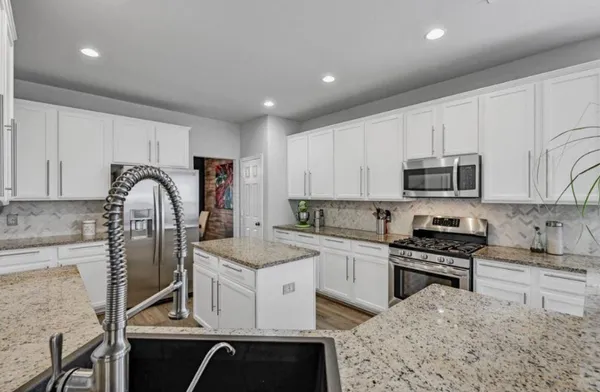 a kitchen with granite countertop stainless steel appliances a sink a stove top oven a counter space and cabinets