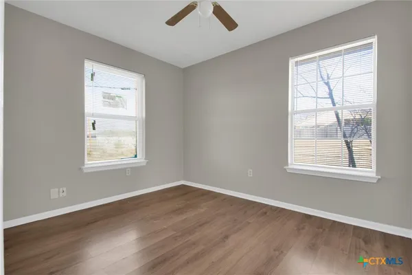 a view of an empty room with a window and wooden floor