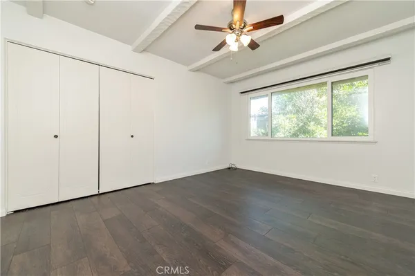 an empty room with wooden floor fan and windows