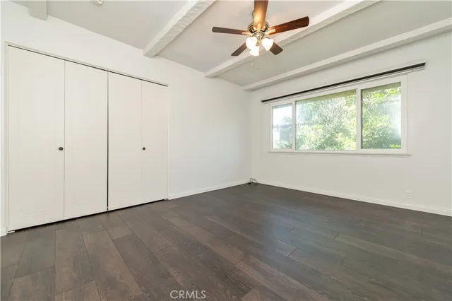 an empty room with wooden floor fan and windows