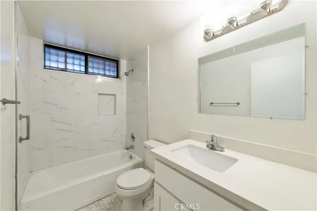 a bathroom with a granite countertop sink toilet mirror and bathtub