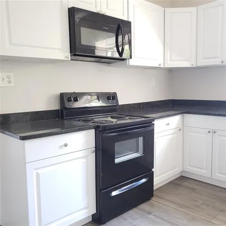 a kitchen with granite countertop white cabinets and black appliances