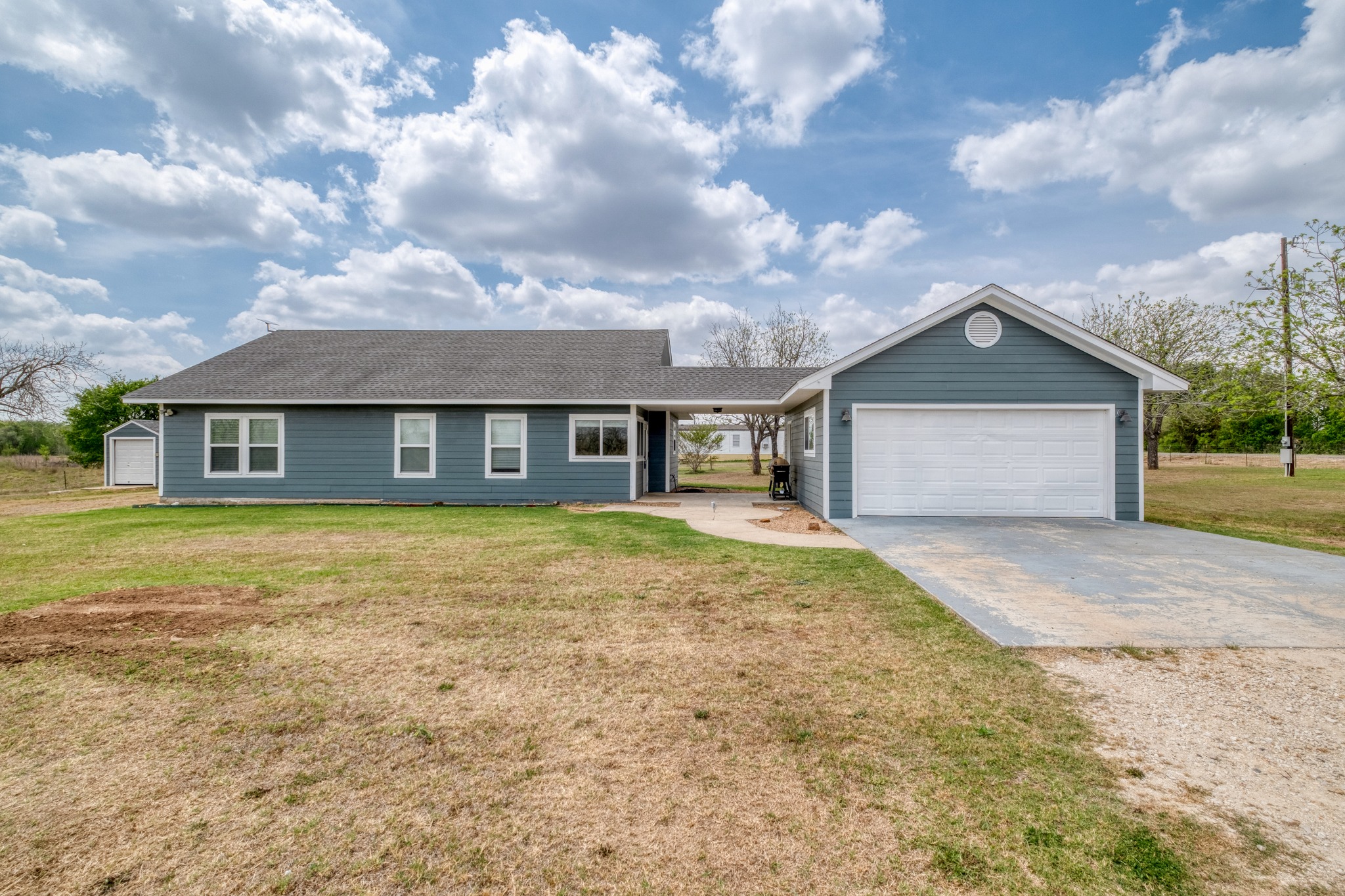 2950 County Road 484 Elgin, TX 78621 - Photo 1 of 25 Ranch-style house featuring a front yard, concrete driveway, a garage, and a shingled roof