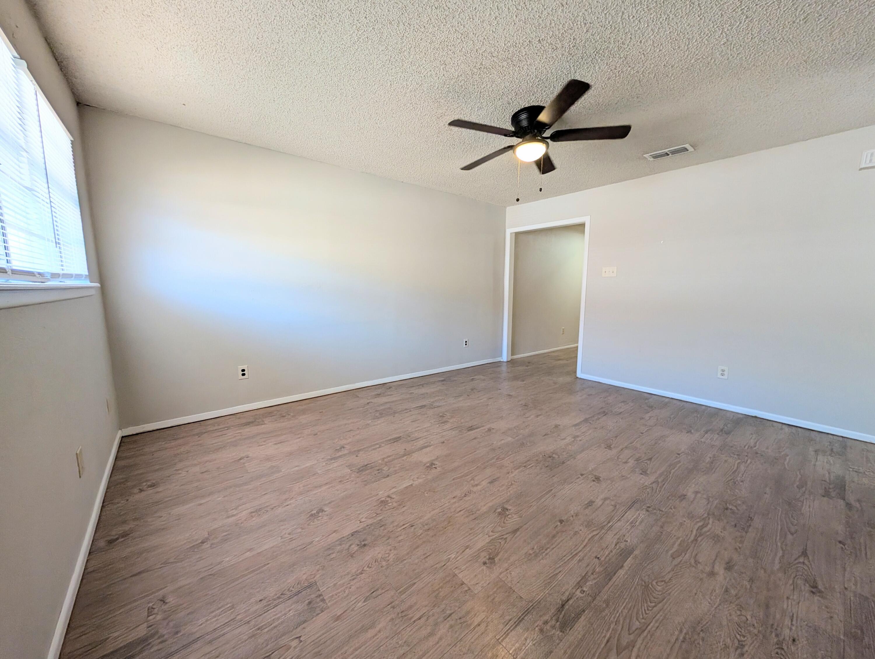 6509 21st Street, Unit B Lubbock, TX 79407 - Photo 2 of 9 an empty room with windows and a ceiling fan