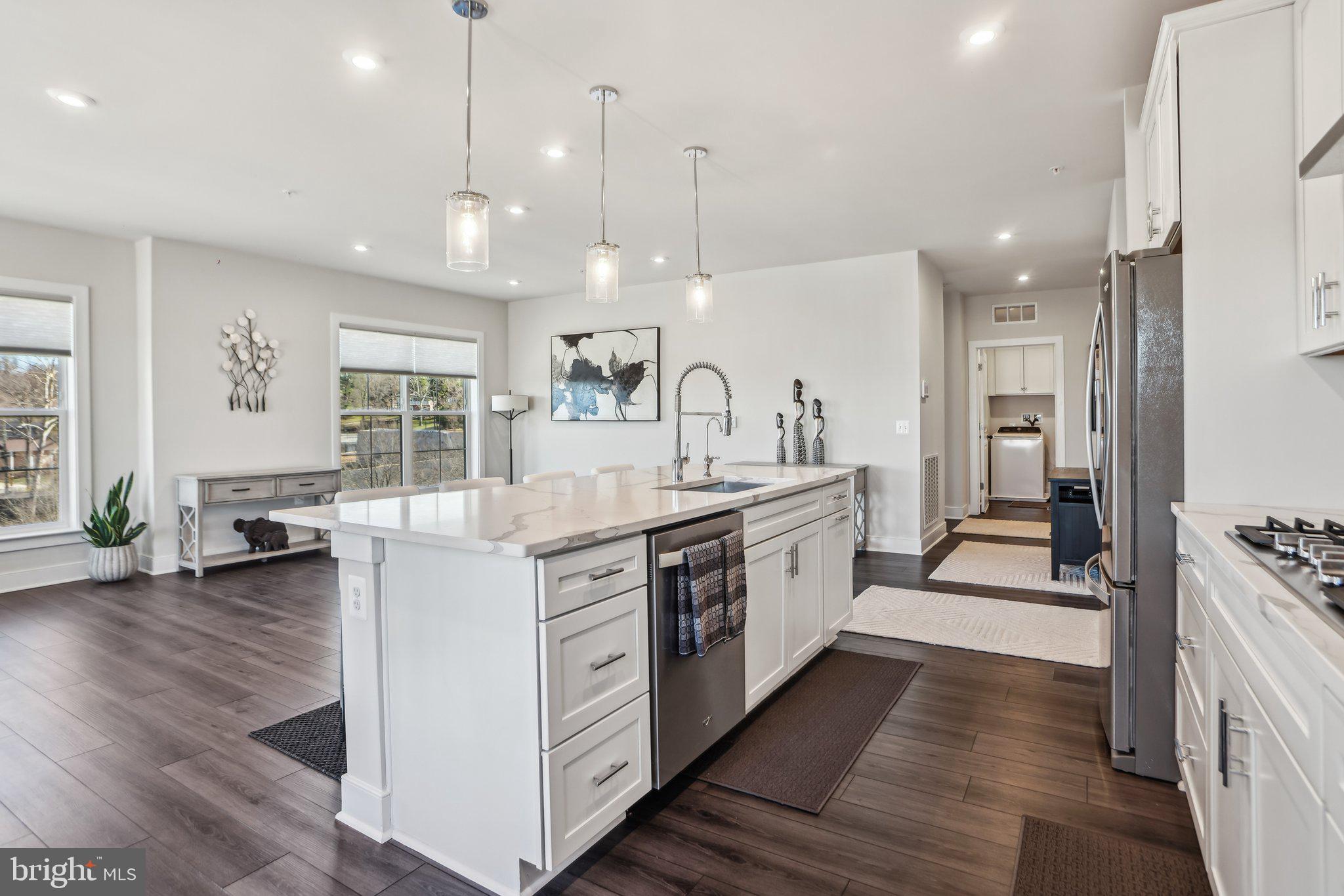 100 St Ives Place, Unit 306 Oxon Hill, MD 20745 - Photo 12 of 32 a large white kitchen with a large center island wooden floor and stainless steel appliances