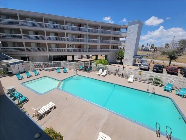 a view of a swimming pool with chairs in front of building