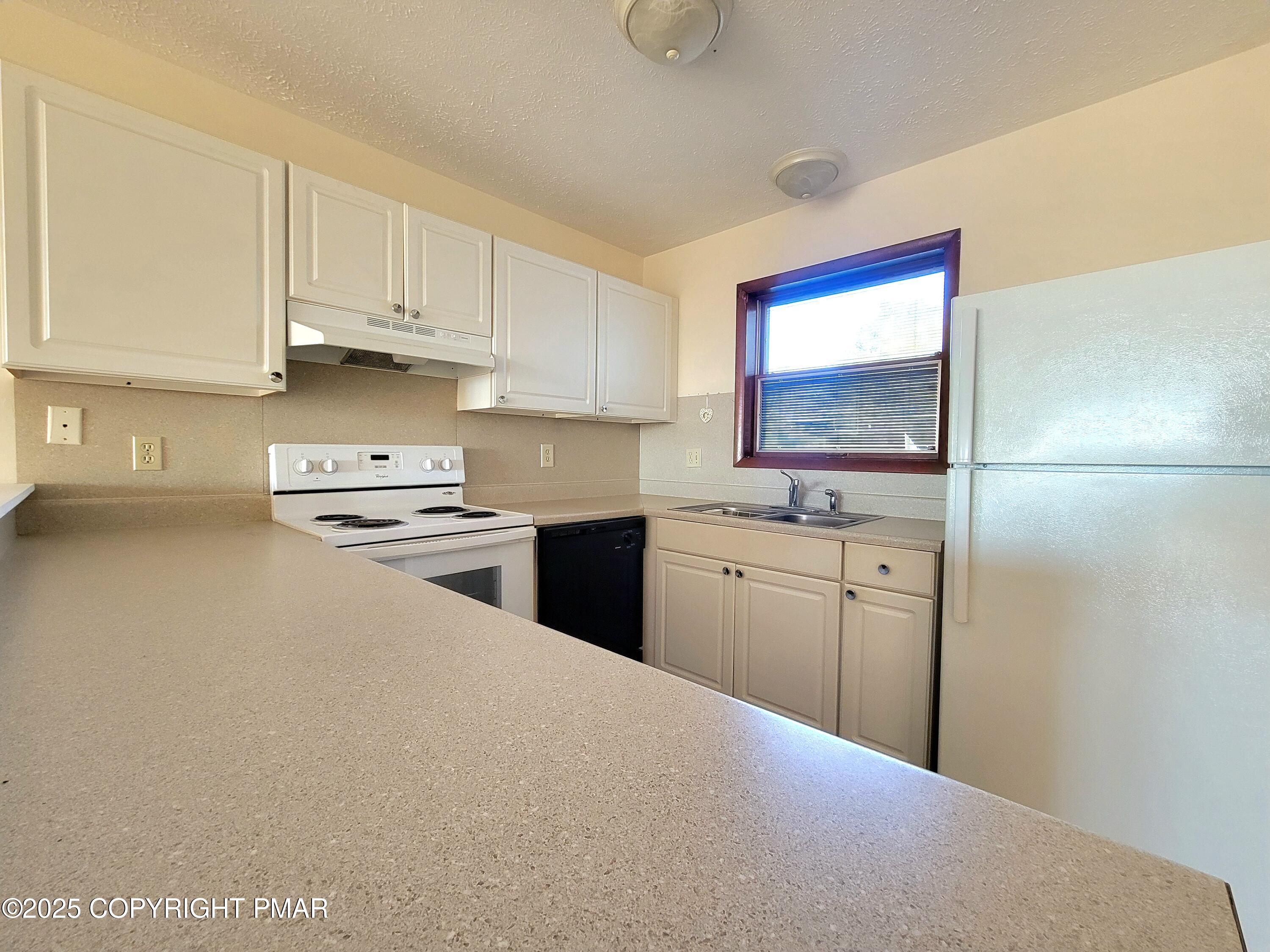115 Foxfire Drive, Unit 306 Mount Pocono, PA 18344 - Photo 6 of 19 a kitchen with white cabinets and white appliances
