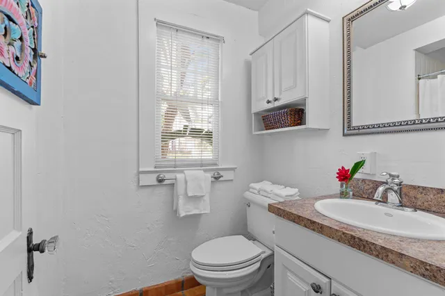 a bathroom with a granite countertop toilet sink and mirror