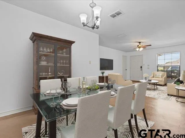 a dining room with wooden floor a chandelier a wooden table and chairs