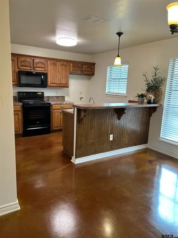 a sink with granite countertop cabinets and window
