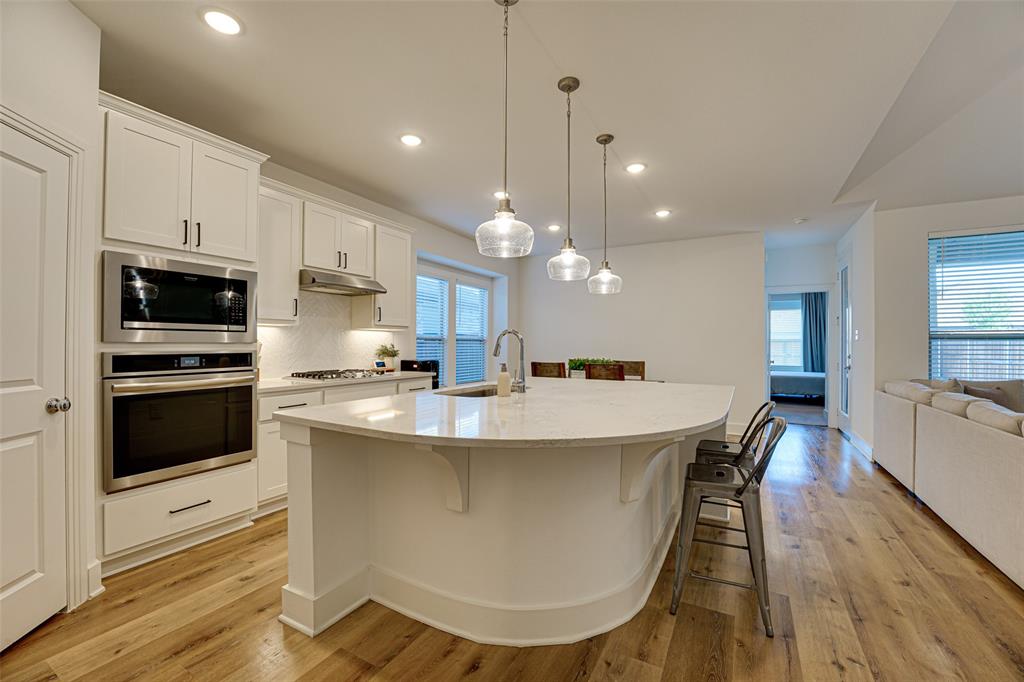 a large kitchen with kitchen island a white cabinets and wooden floor