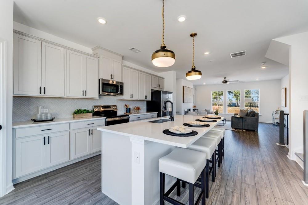 3195 Eastham Run Drive Dacula, GA 30019 - Photo 14 of 35 a kitchen with a sink a stove and chairs with wooden floor