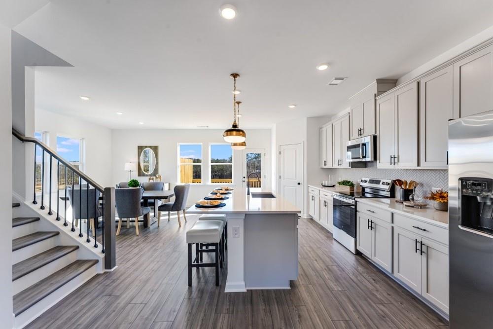 3195 Eastham Run Drive Dacula, GA 30019 - Photo 17 of 35 a kitchen with stainless steel appliances kitchen island granite countertop a stove top oven a sink a dining table and chairs with wooden floor
