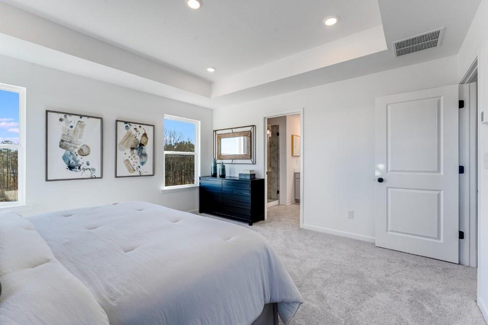 3195 Eastham Run Drive Dacula, GA 30019 - Photo 27 of 35 a spacious bedroom with a large bed a couch and painting on the wall