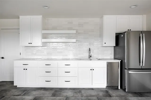 a kitchen with granite countertop white cabinets and refrigerator