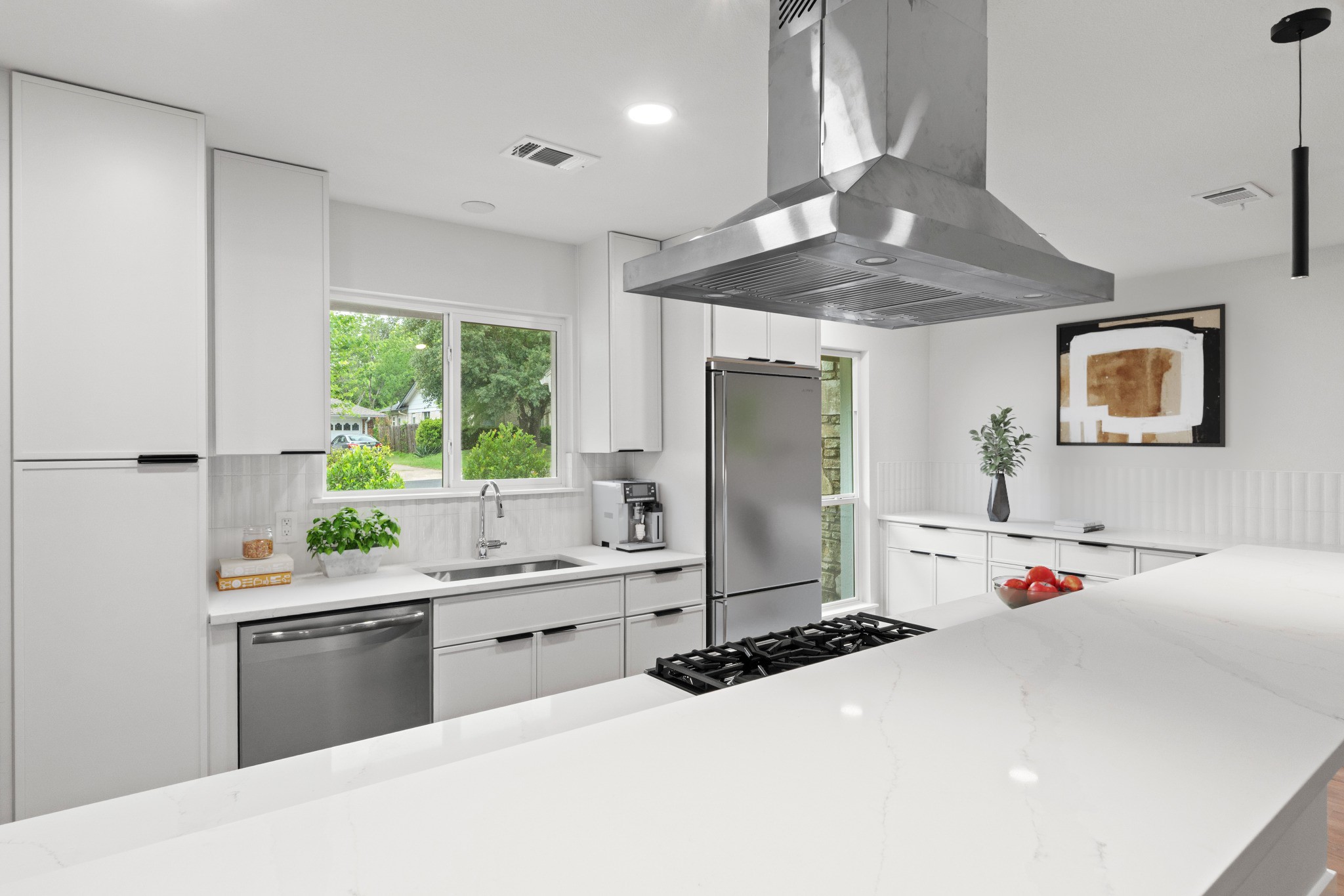 1608 Springer Lane Austin, TX 78758 - Photo 13 of 35 Modern kitchen featuring light-toned cabinetry, stainless steel appliances, a large center island with a light-toned countertop, a gas range with a stainless steel range hood, and a dual-basin undermount sink