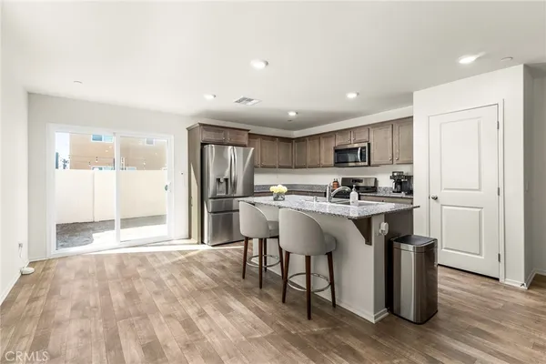 a kitchen with stainless steel appliances granite countertop a sink a stove a refrigerator and island with wooden floor