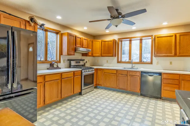 a large kitchen with stainless steel appliances granite countertop a stove a sink dishwasher a refrigerator and cabinets with wooden floor