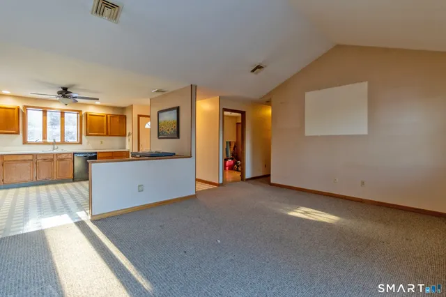 an empty room with a window and kitchen view