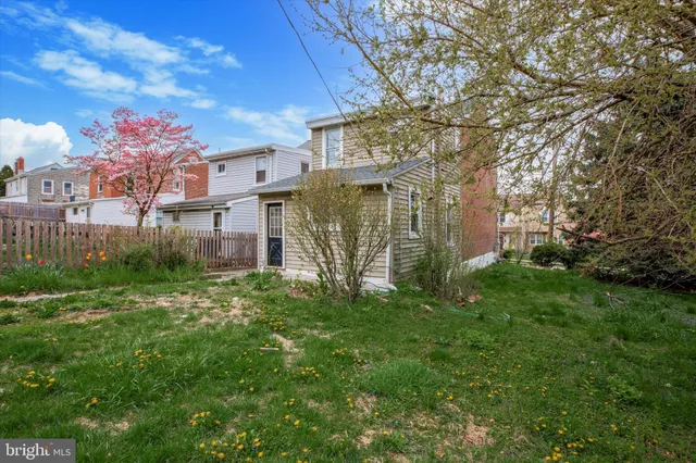 a brick building with a big yard plants and large trees