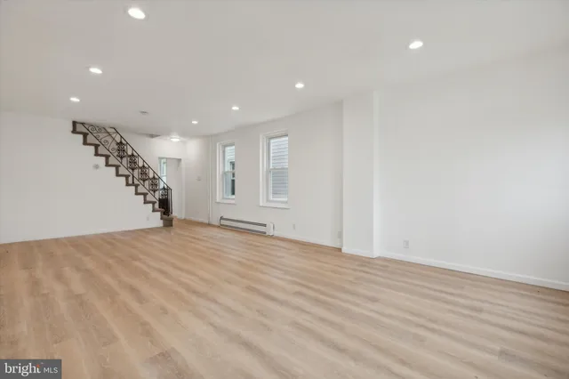 a view of an empty room with wooden floor and entryway