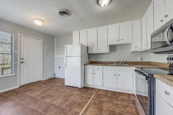 a kitchen with white cabinets and a refrigerator