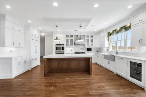 a large white kitchen with stainless steel appliances granite countertop a stove and a sink