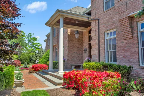 a front view of a house with lots of flowers and trees