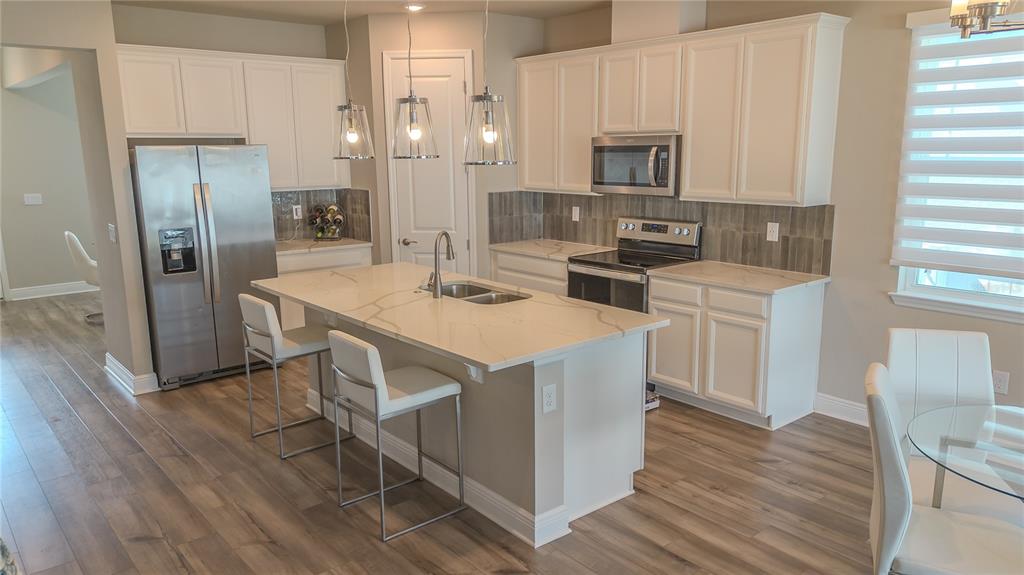 2310 Raven Rdg Drive Minneola, FL 34715 - Photo 5 of 21 a kitchen with stainless steel appliances kitchen island granite countertop a refrigerator a stove a sink and white cabinets with wooden floor