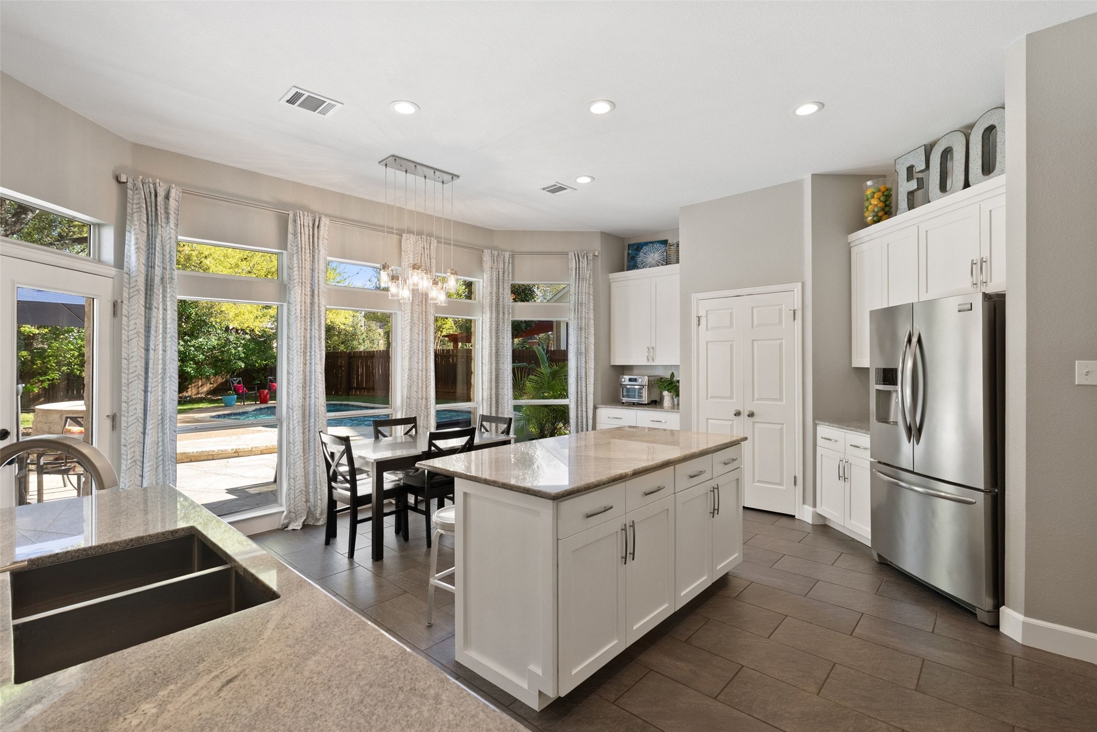 12510 Bright Sky Overlook Austin, TX 78732 - Photo 11 of 39 a large kitchen with kitchen island a large window in it and stainless steel appliances