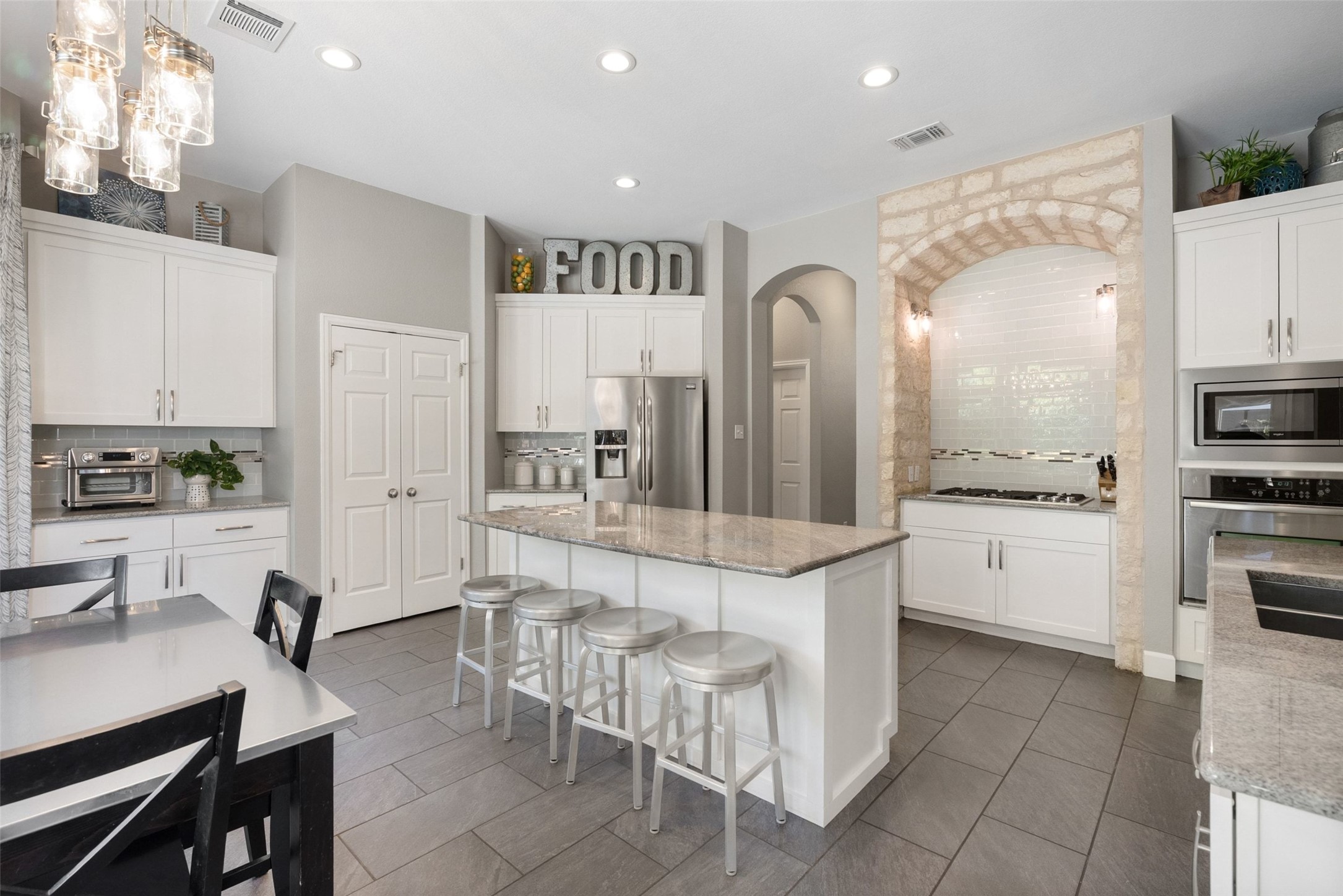 12510 Bright Sky Overlook Austin, TX 78732 - Photo 15 of 39 a large white kitchen with cabinets a island a stove a sink and a refrigerator