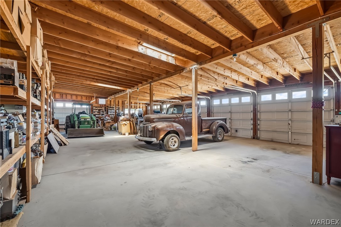 2401 North Stephan Road Kingman, AZ 86401 - Photo 76 of 92 Spacious garage/storage area featuring a concrete floor, multiple garage doors with windows, and exposed wood ceiling joists
