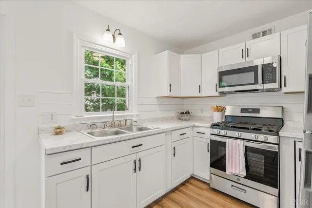 a kitchen with cabinets stainless steel appliances a sink and a window