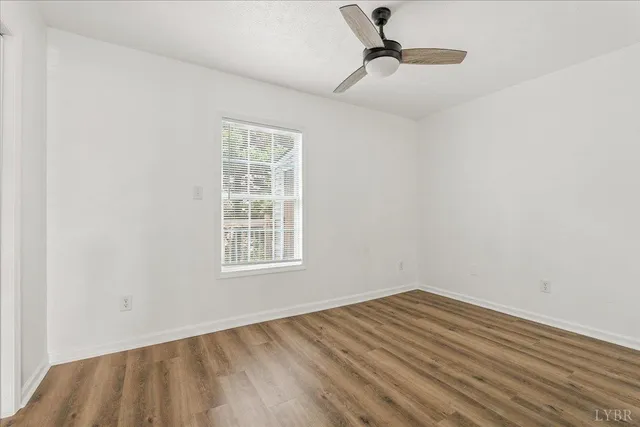 an empty room with a window and wooden floor