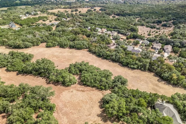 an aerial view of residential houses with outdoor space and trees