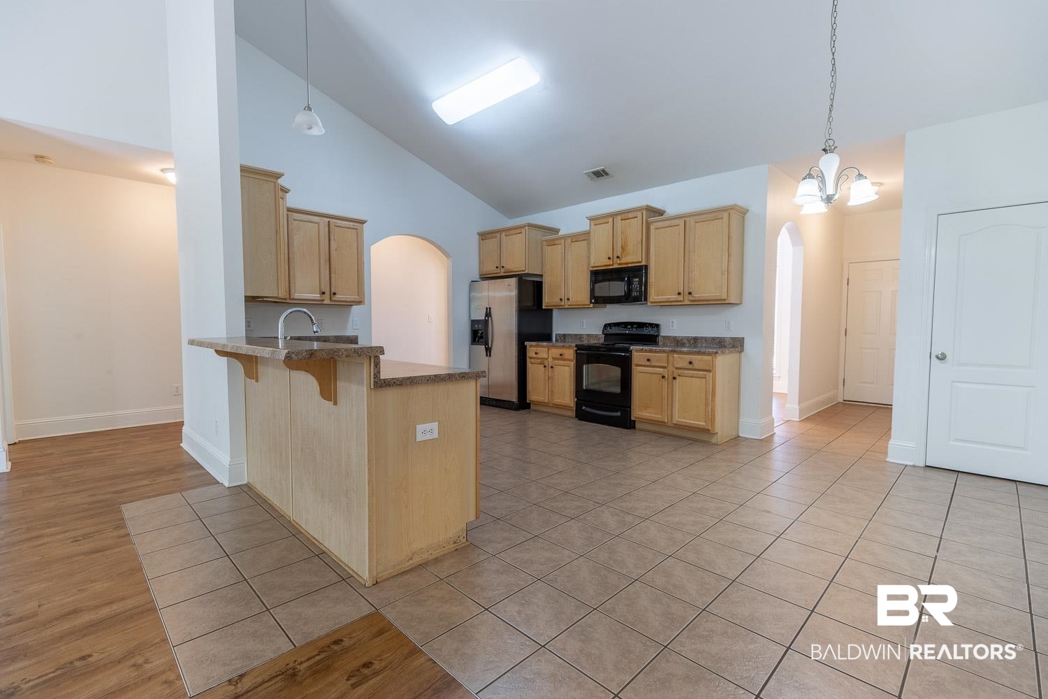 101 Normandy Street Fairhope, AL 36532 - Photo 7 of 18 Kitchen with arched walkways, high vaulted ceiling, a kitchen bar, black appliances, and a peninsula