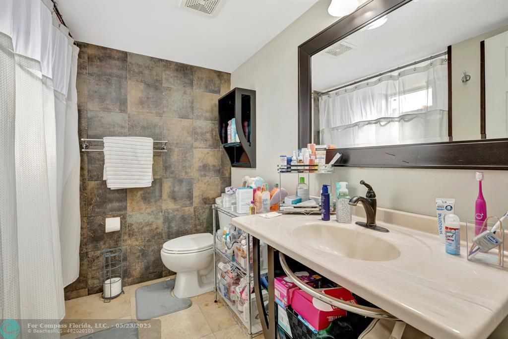 3004 Northeast 5th Terrace, Unit 208C Wilton Manors, FL 33334 - Photo 29 of 63 a bathroom with a sink vanity mirror and toilet