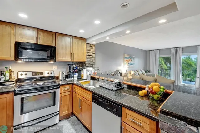 a kitchen with stainless steel appliances granite countertop a sink a stove top oven a counter space and cabinets