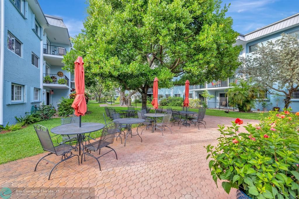 3004 Northeast 5th Terrace, Unit 208C Wilton Manors, FL 33334 - Photo 45 of 63 a view of a table and chairs in patio with a yard