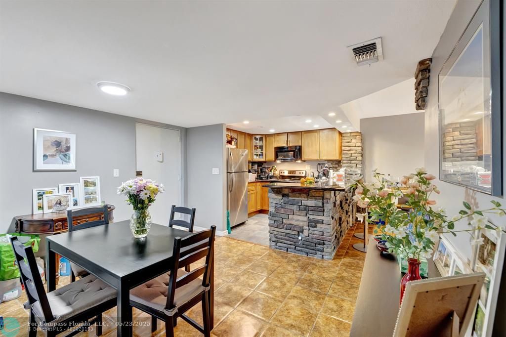 3004 Northeast 5th Terrace, Unit 208C Wilton Manors, FL 33334 - Photo 7 of 63 a kitchen with stainless steel appliances kitchen island granite countertop a table and chairs in it