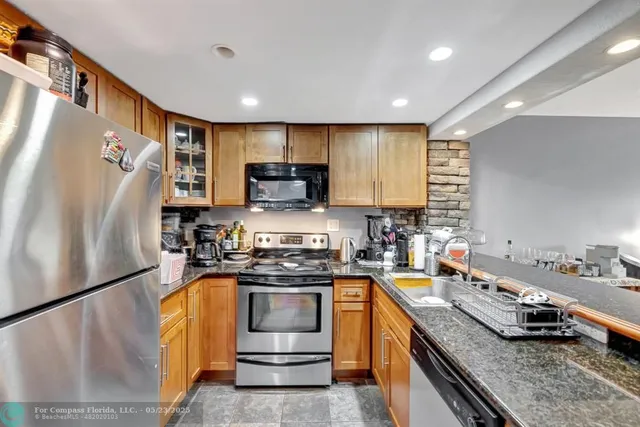 a kitchen with stainless steel appliances granite countertop a refrigerator a stove and a sink