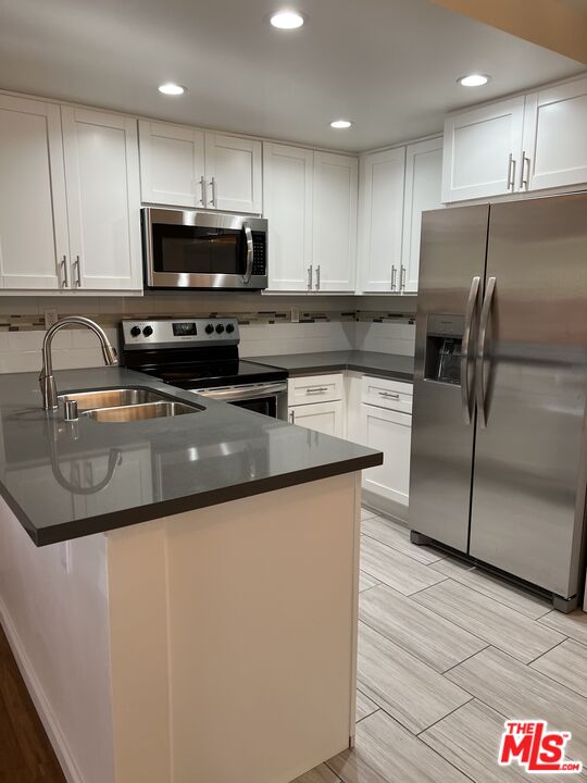 a kitchen with stainless steel appliances granite countertop a sink a stove a refrigerator and a microwave