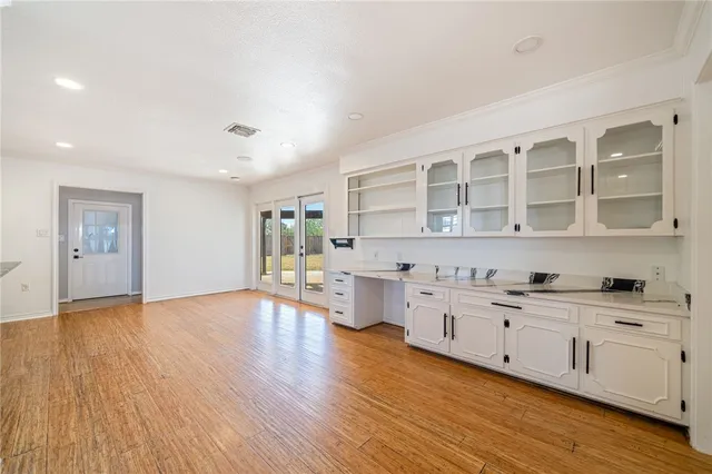 a kitchen with white cabinets and wooden floor