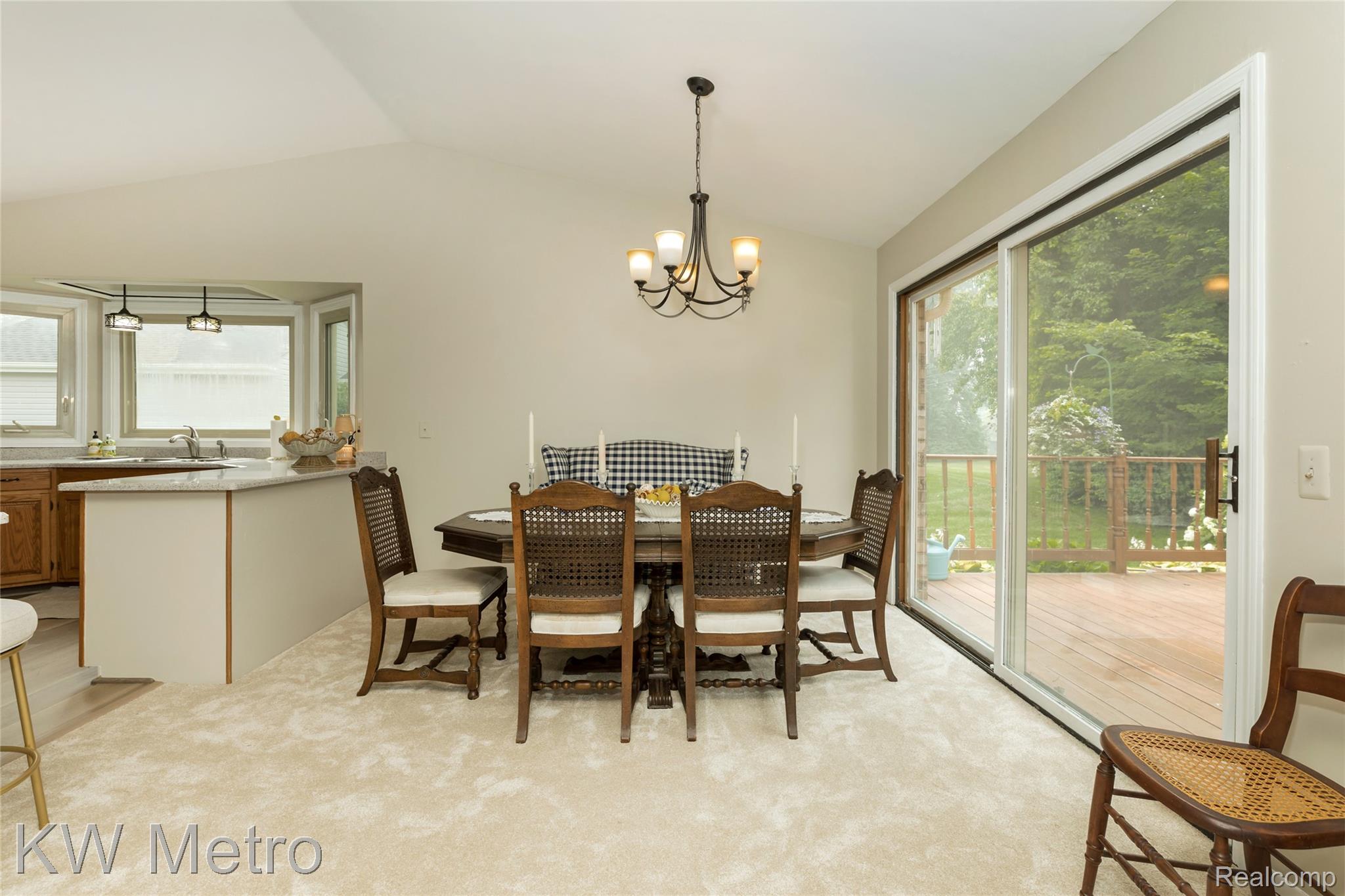 2154 Warrington Road Rochester, MI 48307 - Photo 13 of 41 Dining area featuring a vaulted ceiling with a chandelier, light-toned carpeting, and a sliding glass door opening to a wooden deck